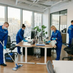 Команда клинеров проводит генеральную уборку офиса: мытье полов, чистка мебели и дезинфекция поверхностей в современном российском офисе